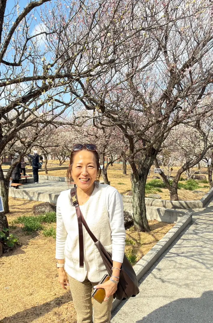 梅の花が咲く公園に立つ作り手の tomomi